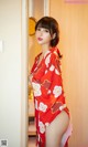 A woman in a red kimono standing in front of a door.