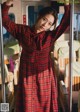 A woman in a red plaid dress standing on a train.