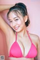 A woman in a pink bikini posing for a picture.