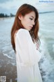 A woman standing on a beach next to the ocean.