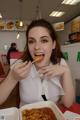 A woman sitting at a table eating a piece of food.